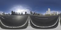 the view of an empty street in front of a city skyline with several lanes running along it