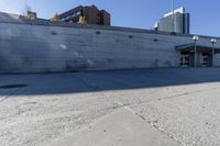 the shadows are cast from a building with high rise buildings in the background at a bus stop