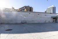 the shadows are cast from a building with high rise buildings in the background at a bus stop