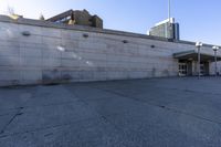 the shadows are cast from a building with high rise buildings in the background at a bus stop