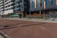 an empty street in front of a tall building with windows and a stop sign on each side