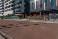 an empty street in front of a tall building with windows and a stop sign on each side