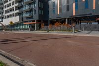 an empty street in front of a tall building with windows and a stop sign on each side