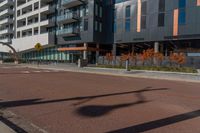 an empty street in front of a tall building with windows and a stop sign on each side