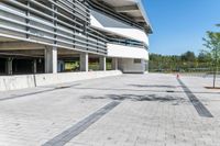 an empty concrete parking lot with trees, stairs and building in background in a public plaza