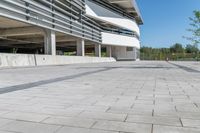 an empty concrete parking lot with trees, stairs and building in background in a public plaza