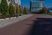 two street signs in a very small area in the sun near some buildings and a car