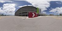 a red sign and some buildings on the ground in a circle with blue sky and clouds