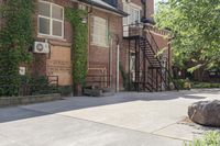 the steps leading to this building are next to a tree and a brick wall in the background