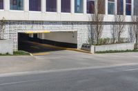 an empty street next to a large building with no windows on it and a long driveway