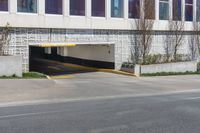 an empty street next to a large building with no windows on it and a long driveway