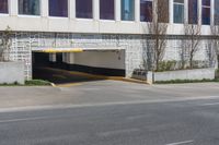 an empty street next to a large building with no windows on it and a long driveway