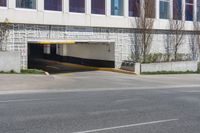 an empty street next to a large building with no windows on it and a long driveway