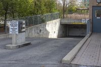 a concrete ramp is attached to a gray concrete wall under a bridge with a sign warning pedestrians on it