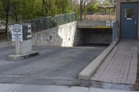 a concrete ramp is attached to a gray concrete wall under a bridge with a sign warning pedestrians on it