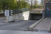 a concrete ramp is attached to a gray concrete wall under a bridge with a sign warning pedestrians on it