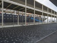 a train station with some cars parked outside of it by a fence and cobblestone walkway