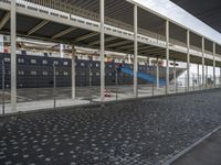 a train station with some cars parked outside of it by a fence and cobblestone walkway