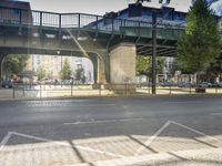 a black van is driving on the street below a bridge with a bicycle leaning against it