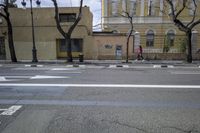 a person is crossing the street in front of an old building and cars on the street
