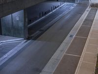 a long tunnel with a light at the end next to a parking area with people