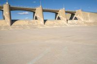 a concrete road with sand piles in front of it and some large pillars above it