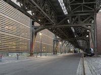 an empty street below an elevated bridge in an urban area of the city during the day