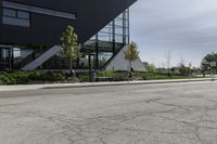 the curb in front of a modern building on a street corner with grass in the center