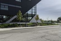 the curb in front of a modern building on a street corner with grass in the center