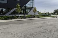 the curb in front of a modern building on a street corner with grass in the center