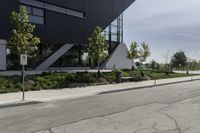 the curb in front of a modern building on a street corner with grass in the center