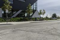 the curb in front of a modern building on a street corner with grass in the center