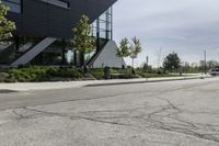 the curb in front of a modern building on a street corner with grass in the center