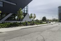 the curb in front of a modern building on a street corner with grass in the center