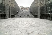 a walkway that has a number of steps and different building buildings in the background with people walking on them