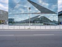 a view of the side of a building that has a large curved building and there is a fence near the street