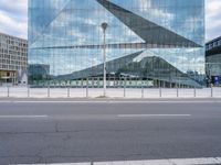 a view of the side of a building that has a large curved building and there is a fence near the street