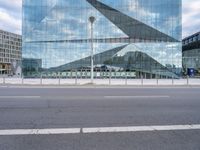 a view of the side of a building that has a large curved building and there is a fence near the street