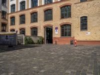 a sidewalk with chairs next to the brick building on the side, some have stairs and some buildings in the background