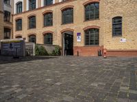 a sidewalk with chairs next to the brick building on the side, some have stairs and some buildings in the background