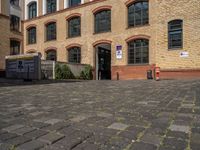 a sidewalk with chairs next to the brick building on the side, some have stairs and some buildings in the background