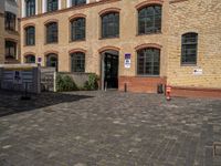 a sidewalk with chairs next to the brick building on the side, some have stairs and some buildings in the background