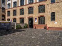 a sidewalk with chairs next to the brick building on the side, some have stairs and some buildings in the background