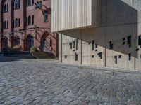 cobblestone driveway surrounded by modern buildings on sunny day with sun reflecting onto the windows