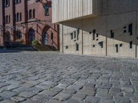 cobblestone driveway surrounded by modern buildings on sunny day with sun reflecting onto the windows