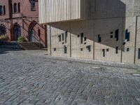 cobblestone driveway surrounded by modern buildings on sunny day with sun reflecting onto the windows