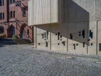 cobblestone driveway surrounded by modern buildings on sunny day with sun reflecting onto the windows