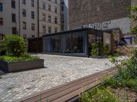 several plants sit in decorative concrete planters along the sidewalk of a building that is very modern