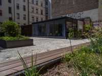 several plants sit in decorative concrete planters along the sidewalk of a building that is very modern