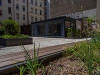 several plants sit in decorative concrete planters along the sidewalk of a building that is very modern